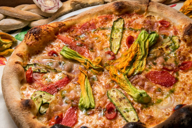 istock pizza with sliced zucchini, courgette flowers, tomatoes and ham, 1289950458