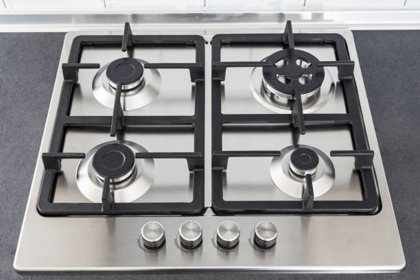 istock Closeup a gas stove burner and cast iron grate. Stainless steel kitchen surface. 1289951220