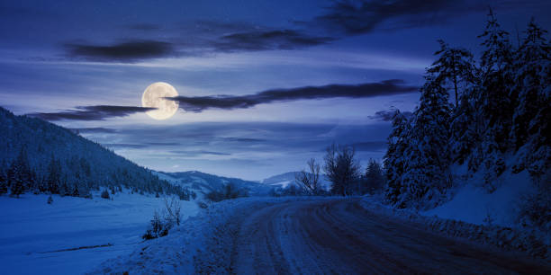 istock road through mountain landscape in winter at night 1289956467
