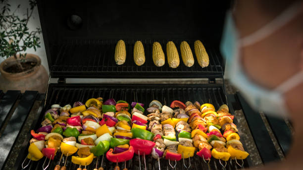 istock Chef using a face mask and cooking a skewers with corn on bbq during COVID-19 1289958494