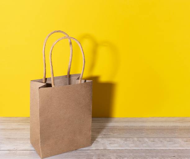 istock brown recycled paper bag with yellow background and copy space for gift or purchase 1289963530