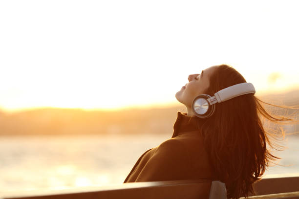 woman listening to music breathing on a bench in winter - music listening women relaxation imagens e fotografias de stock