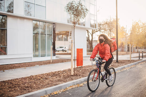 istock Woman with face mask doing food delivery on bicycle 1289966767