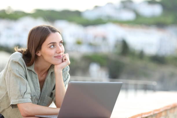 Satisfied woman with laptop thinking looking at side Satisfied woman with laptop thinking looking at side town of hope stock pictures, royalty-free photos & images