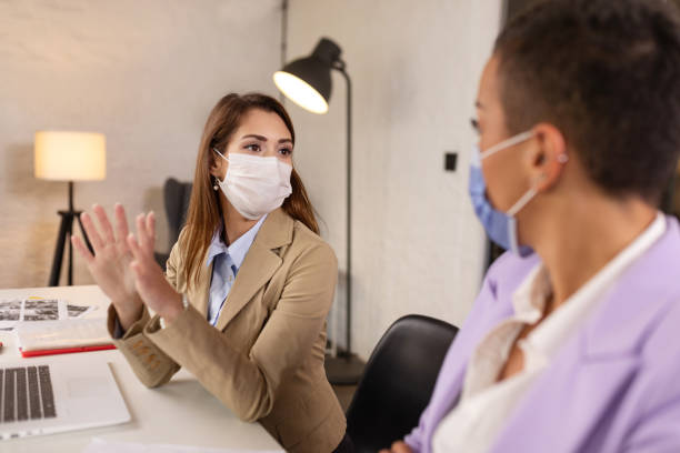 istock Two beautiful businesswomen wearing protective face masks and talking 1289970272