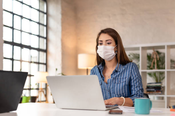 istock Businesswoman working on a laptop while wearing a protective mask 1289972098
