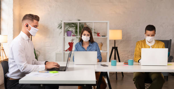 istock Young coworkers wearing protective face masks while working in the office 1289972175