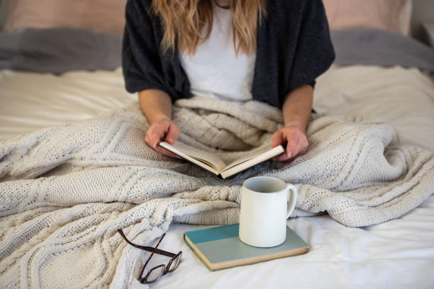 istock A young woman reading on her bed while drinking coffee in a cozy home. 1289974074