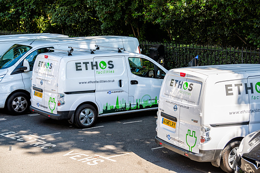 London, UK - June 22, 2018: Downtown city parking lot with road street and parked trucks vans and sign for Ethos facilities zero emissions cleaning services