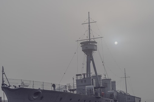 Belfast, Northern Ireland, United Kingdom - December 6, 2020: HMS Caroline, a warship, moored in Belfast Harbour on a foggy morning.