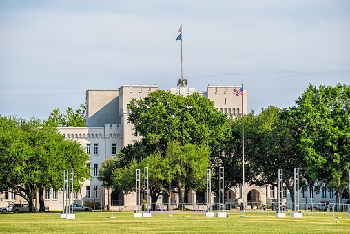 Charleston, USA - May 12, 2018: Citadel Military College of South Carolina university exterior of clock tower building and American flag with green grass lawn