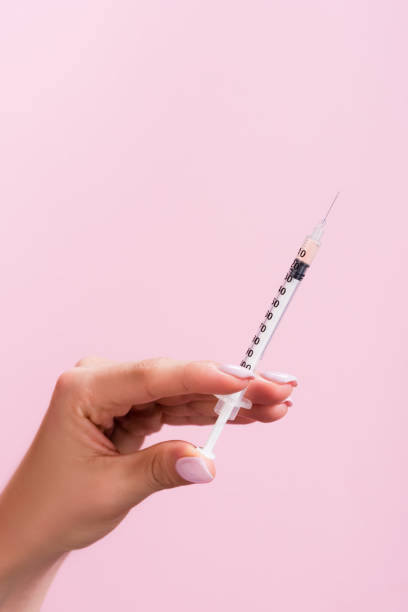istock cropped view of hand with syringe isolated on pink 1289981748