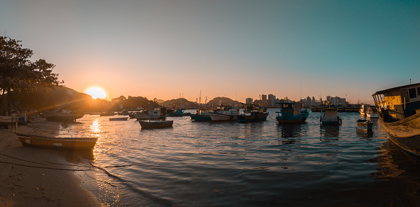 view of Prainha beach in Vila Velha city overlooking the bay with boats, and vitoria city at sunset