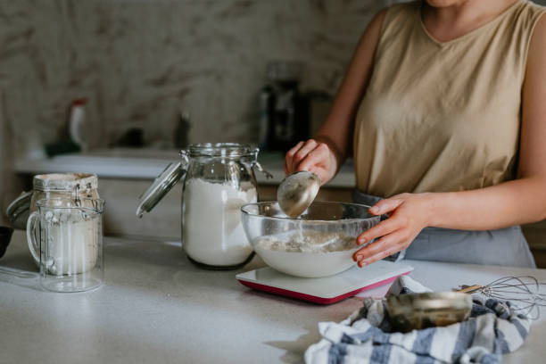 istock Home Hobbies: an Unrecognizable Woman Baking Sourdough Bread from Scratch - Adding Flour to the Dough 1289989224