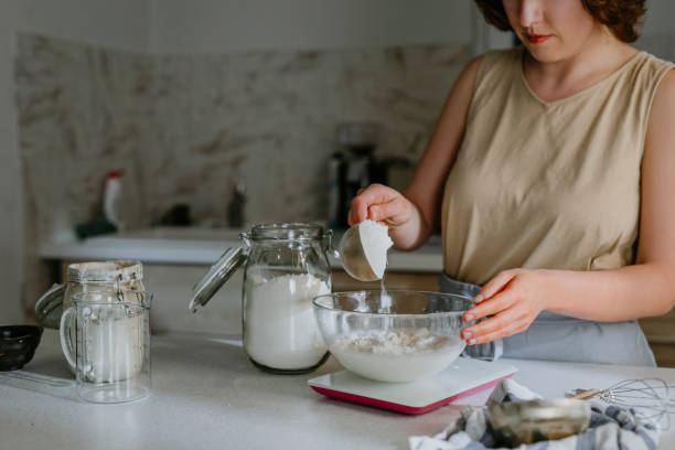 istock Home Hobbies: an Unrecognizable Woman Baking Sourdough Bread from Scratch - Adding Flour to the Dough 1289989235