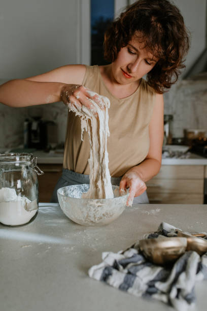 istock Home Hobbies: a Smiling Woman Baking Sourdough Bread from Scratch - the Kneading Phase 1289989245