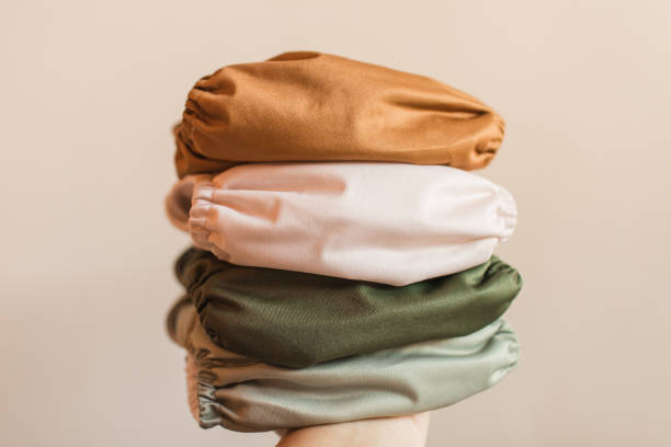istock A Woman Holding a Stack of Modern Neutral-Colored Reusable Cloth Diapers with a Neutral Background in Bright Natural Light 1289991633