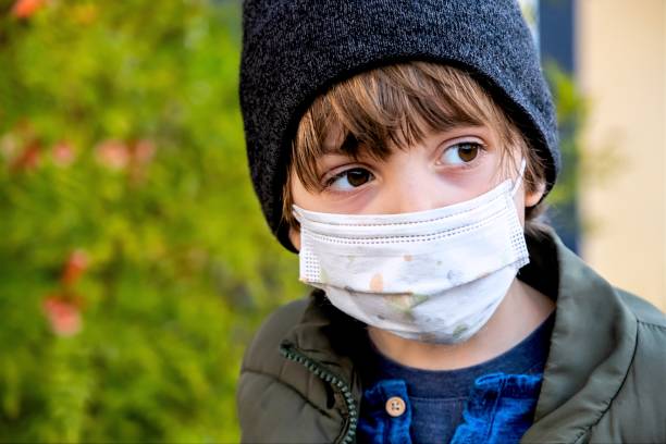 istock Serious pensive Little child schoolboy looking away using a protective face mask 1289991715