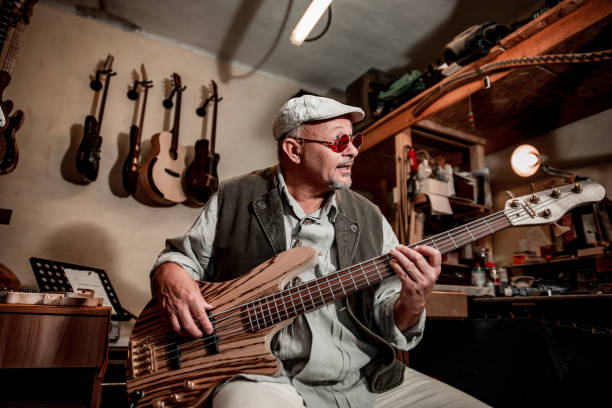 istock Senior Man Singing and Playing on a Guitar in Instrument Maker's Workshop 1289993623
