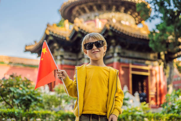 godersi le vacanze in cina. ragazzo con bandiera nazionale cinese a città proibita. viaggia in cina con il concetto di bambini. transito senza visto 72 ore, 144 ore in cina - travel locations europe china beijing foto e immagini stock