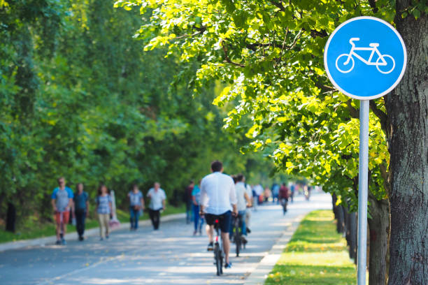 自転車レーン、夏の緑の公園で自転車道の看板。自転車や歩行者のサイクリスト。休息とリラクゼーションの概念、運動、健康的なライフスタイル - 歩行者 ストックフォトと画像