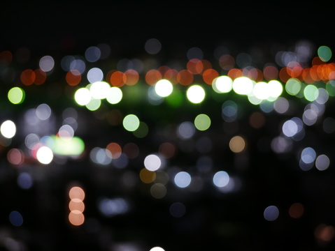 Close-up of illuminated traffic lights and raindrops seen through transparent glass on street.