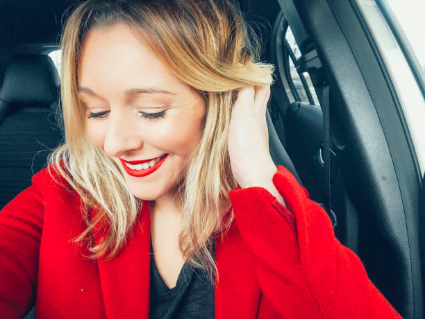 Beautiful woman portrait holding hair blonde Portuguese red lipstick dressed for Christmas in red - fotografia de stock