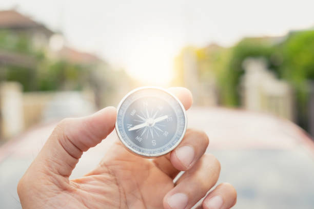 istock Man hand holding compass on city and car blurred background Using wallpaper or background travel or navigator image.