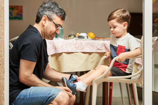 istock Father helping his little son put on shoes 1290022769