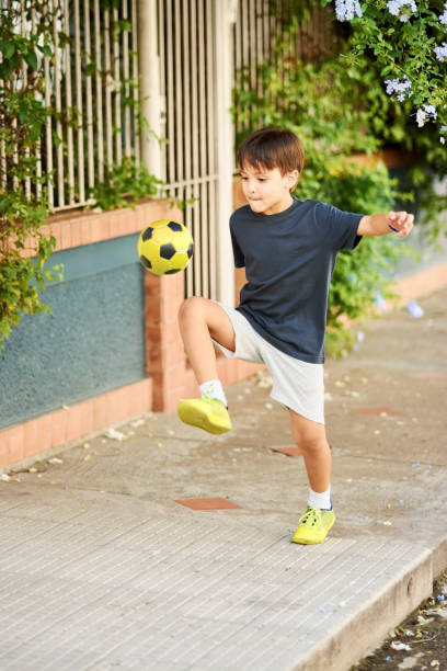 istock Boy playing with football on sidewalk 1290023470