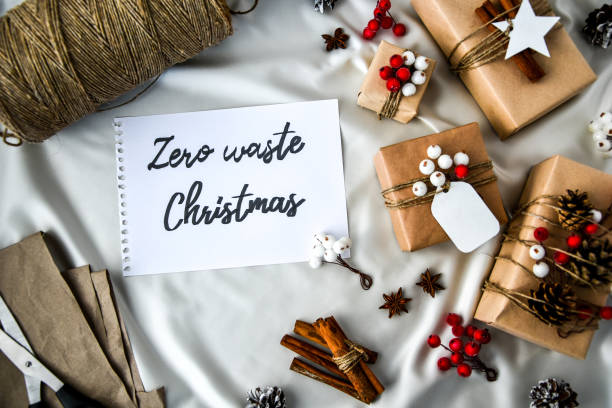 istock Zero waste Christmas text with presents with decorations on champagne colored silk background. Copy space. Eco friendly packed gift with tags from craft cardboard 1290025906