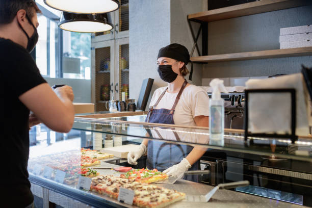 istock Smiling behind the face mask and serving customer over the counter 1290028899