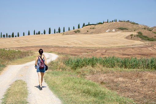 At Asciano - Italy - On august 2020 - girl hiking in Val d'Orcia countryside and so called crete senesi