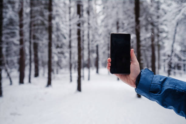 istock cell phone in a man's hand against a beautiful snowy winter forest background 1290033475