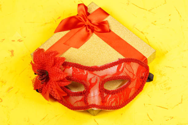 istock Colored square gift box on concrete background and red carnival mask, flat lay, top view 1290034299