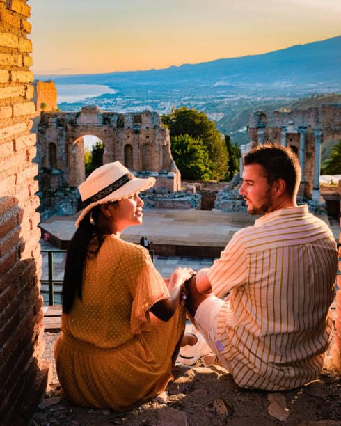 taormina sicília, casal assistindo pôr do sol nas ruínas do teatro grego antigo em taormina, sicília - sicily taormina mt etna italy - fotografias e filmes do acervo