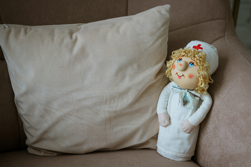 Doctor doll on a chair with a pillow. Health and children's medicine concept