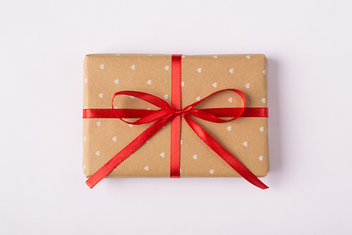 Above close up view photo of one single cute present with red ribbon wrapped in craft paper isolated white backdrop
