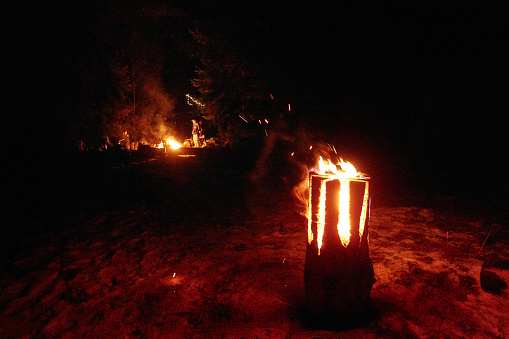 Swedish or finnish log candle. Fire burning from inside the wooden log at night. Cooking on a fire.