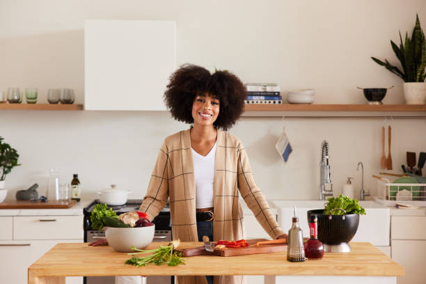 istock Smiling young woman preparing a meal at her kitchen island 1290042364