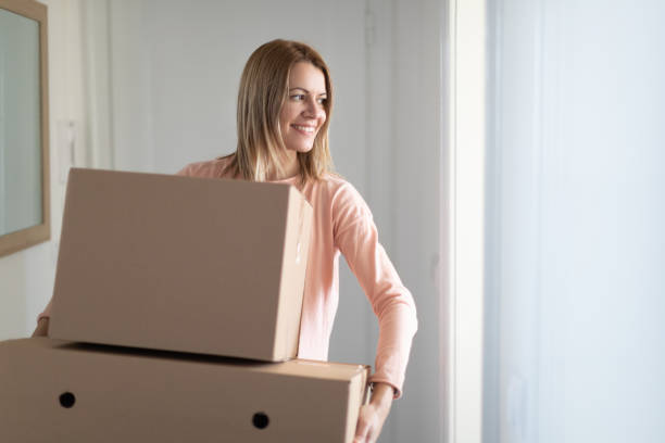istock Woman carrying stacked boxes into new home and smiling 1290045205