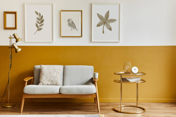 istock Unique living room in modern style interior with design sofa, elegant gold coffee table, mock up poster frames, flowers in vase, decoration and pesronal accessories in home decor. Template. 1290048743