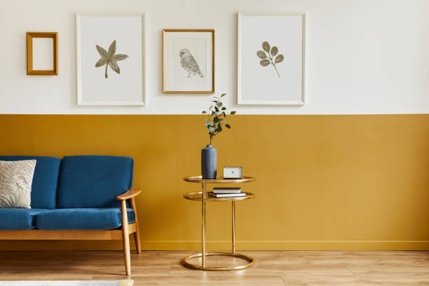istock Unique living room in modern style interior with design sofa, elegant gold coffee table, mock up poster frames, flowers in vase, decoration and pesronal accessories in home decor. Template. 1290048828