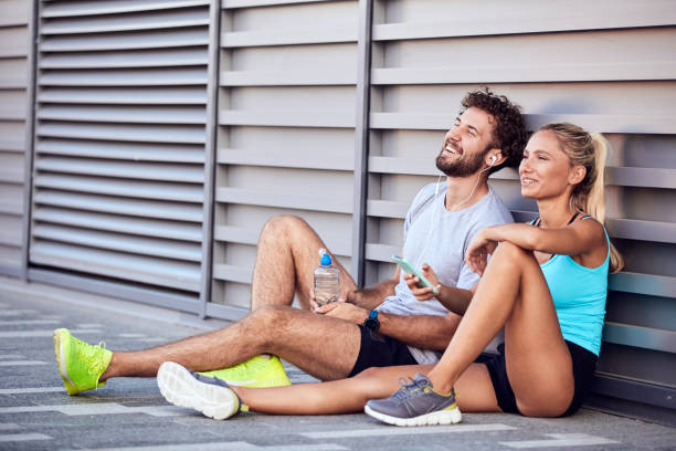 casal urbano moderno fazendo pausa na calçada durante a corrida / exercício. - couple stretching running jogging - fotografias e filmes do acervo