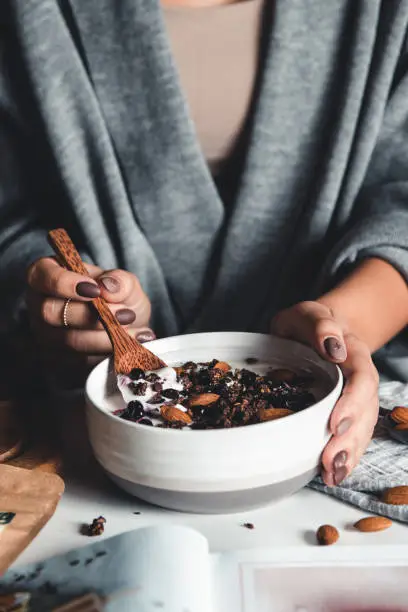 Photo of Closeup of bowl with fresh oatmeal and spoon in woman hands, healthy and nutritive breakfast concept.