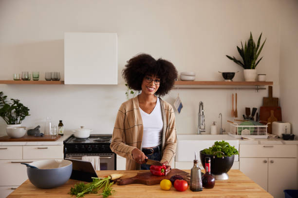 istock Smiling young woman chopping fresh vegetables in her kitchen 1290049907