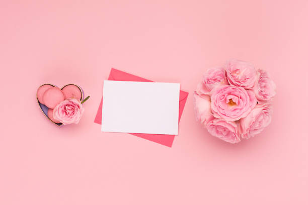 istock Flowers roses, envelope and sweets macaroons on pink background. Valentines day concept. Flat lay, top view, copy space. 1290050904