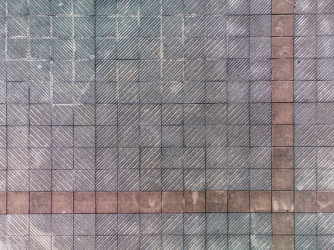 Aerial view of some dirty and old tiles on a sidewalk in a city.