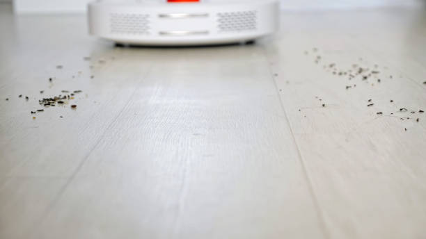 istock Robot vacuum cleaner with red lamp drives to scattered trash 1290056882
