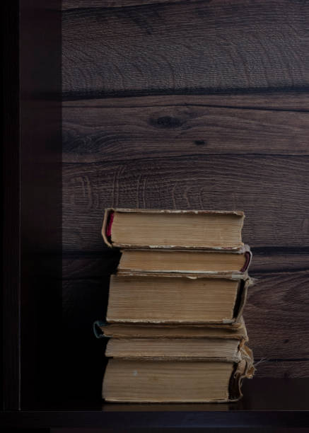 istock Messy stack of old paper books on dark shelf, vertical image 1290059439